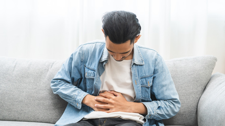 Man holding abdomen suggesting trapped wind