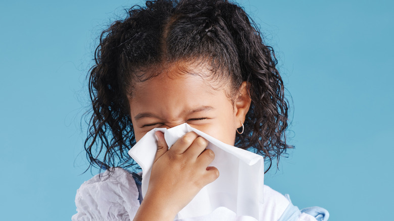 Young girl blowing her nose with handkerchief