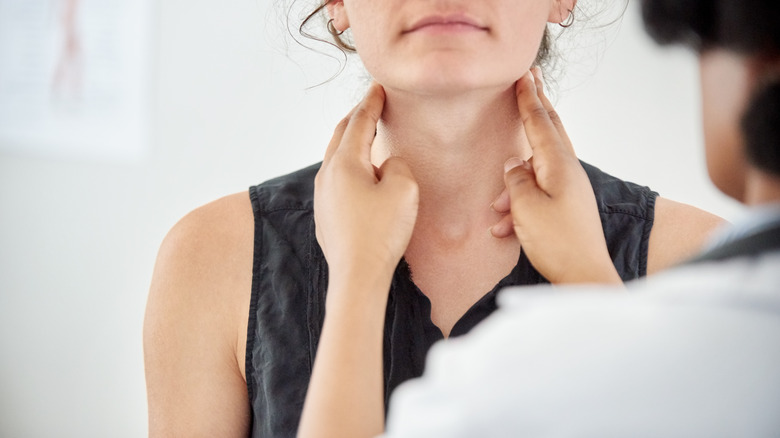 Doctor performing a thyroid exam on female patient