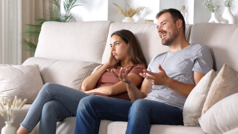 Bored woman listening her partner sitting on a couch at home