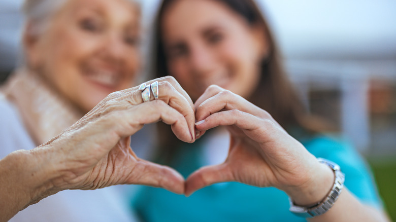 Two women making a heart shape with their hands