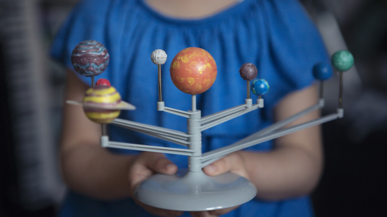 A child is holding a model of the solar system