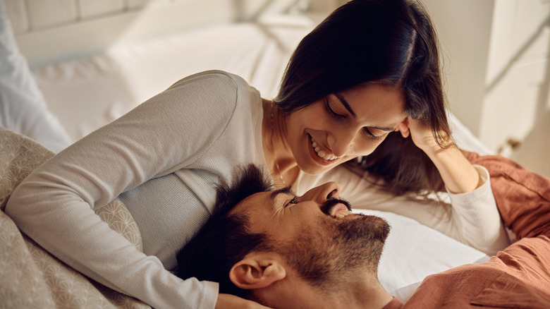 Happy couple in love communicating face to face while relaxing on a bed.