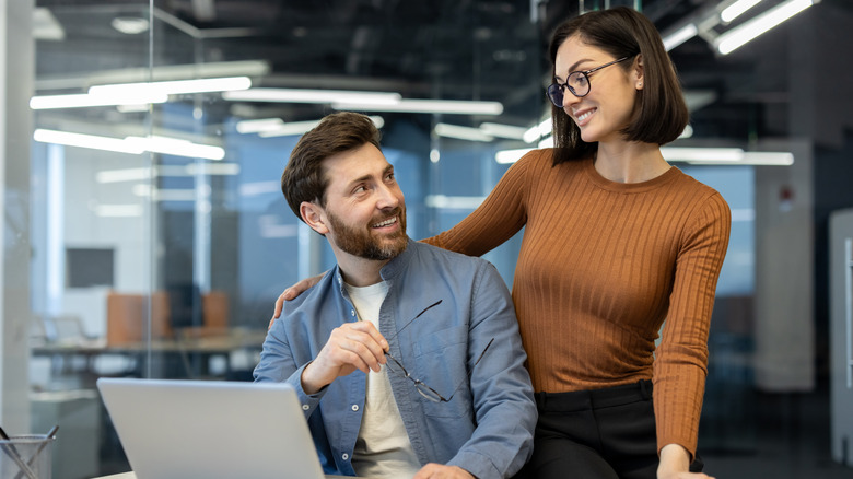 Woman flirts with man at workplace inside office