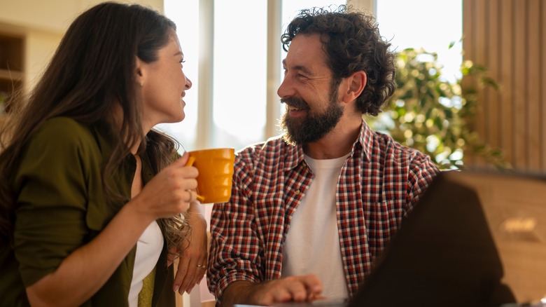Happy couple talking and enjoying coffee at home