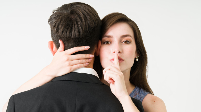 A woman with a secret is hugging a man