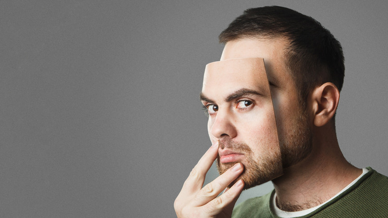 A man is holding a mask of himself