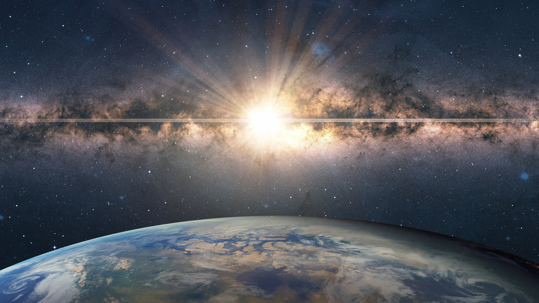 Computer rendering of a supernova explosion occurring in the milky way above a blue earth