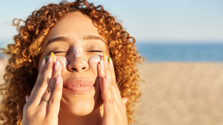 Young woman applying sunscreen to her face