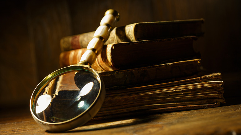 A magnifying glass resting against stack of old books.