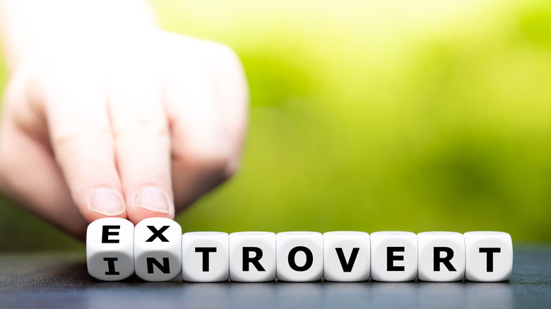 Hand turning over letter cubes to replace introvert