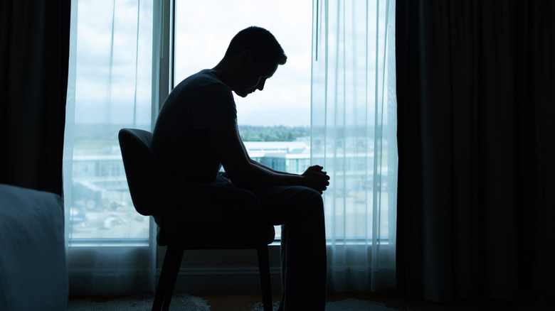 Man sitting in dark room by himself