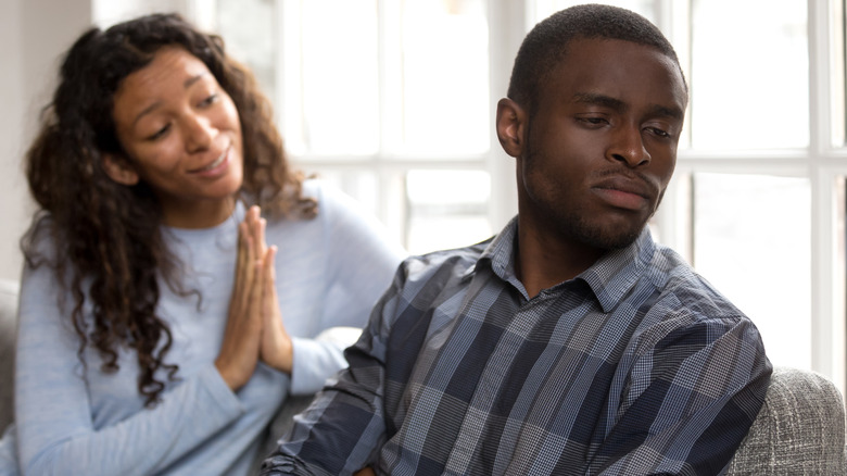 Woman trying to apologize to her partner, who has turned away