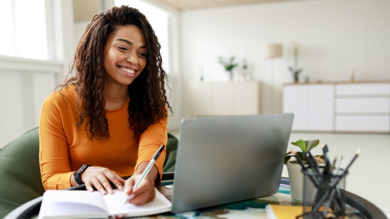 Woman smiling as she makes handwritten notes