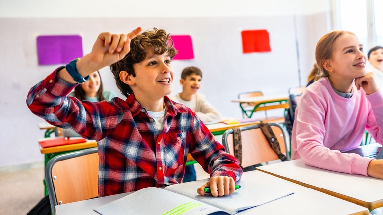 Child raising hand in class to answer a question