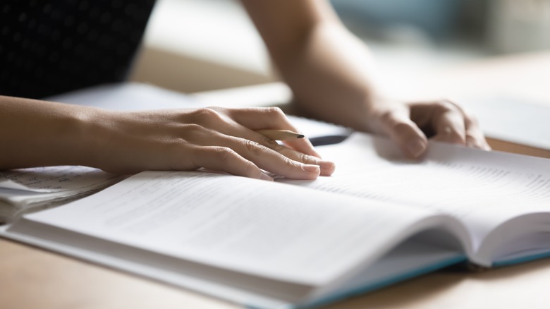 Student preparing handwritten notes from textbook