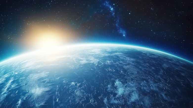 Sun rising behind Earth and illuminating space