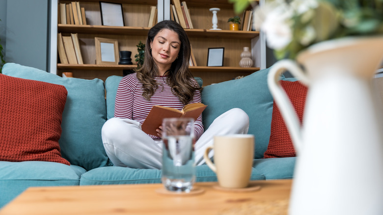 Woman reading a book while sitting on couch