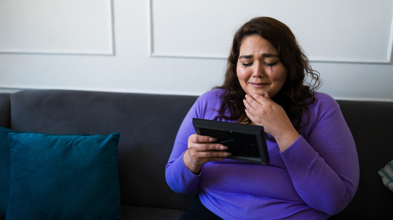 Woman crying while looking at a framed photo