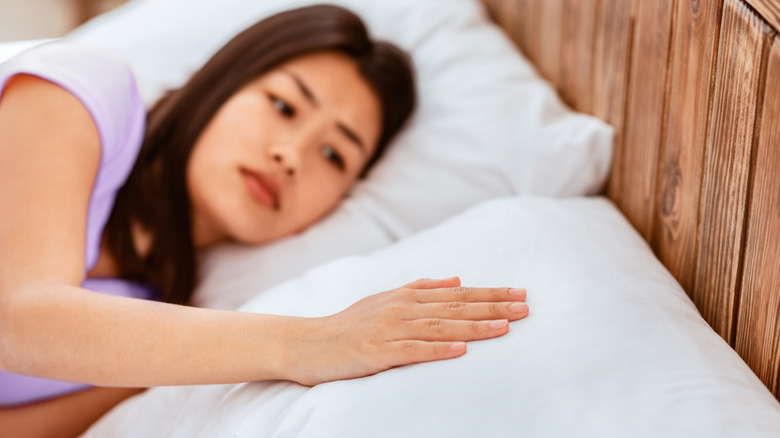 A woman with hand on empty pillow