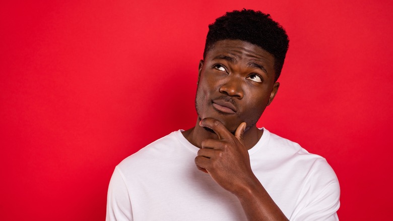 Man with hand on chin against red wall