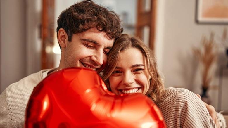 A couple behind a red heart-shaped balloon