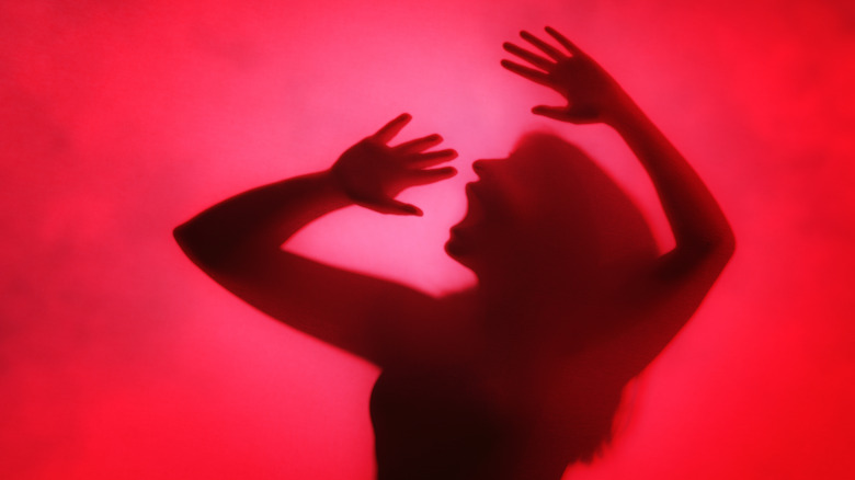 Woman screaming against red background