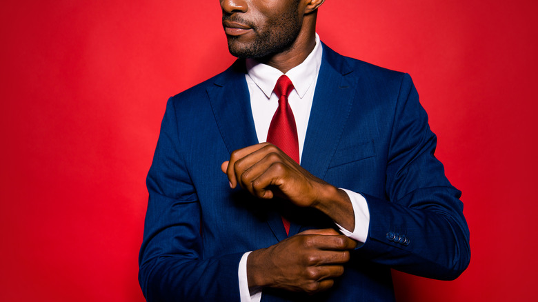 Man wearing a red tie and blue suit against a red background