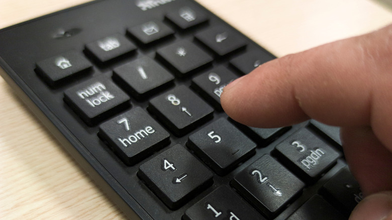 Person pressing keys on small number pad