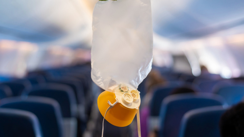 An oxygen mask hangs in the cabin of an airplane