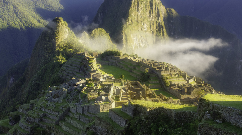 The Inca citadel of Machu Picchu, white misty clouds and Huayna Picchu mountain in the background, Peru.