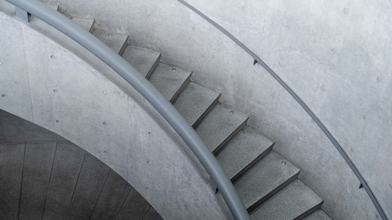 A modern, curving concrete staircase in monochrome shades of gray