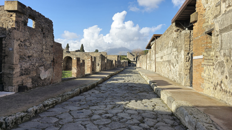 A cobbled street among the ruins of Pompeii, Italy, with Mt. Vesuvius in the background