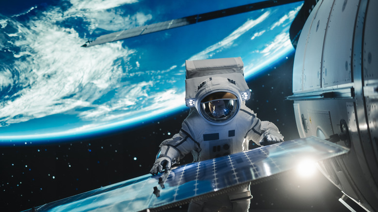 Astronaut examining exterior of spacecraft, wearing spacewalking suit