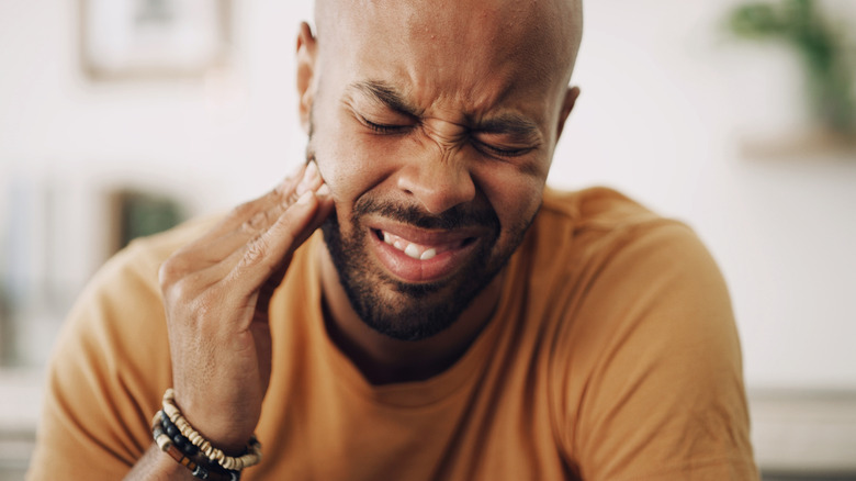 Man touching side of face from tooth pain