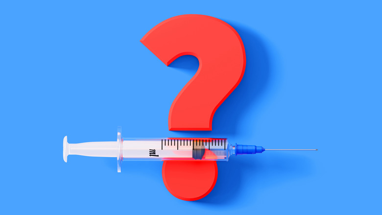 Concept of a syringe laying between a red question and its period