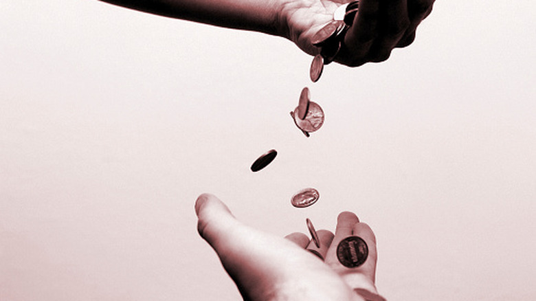 One hand dropping pennies, another hand catching them.