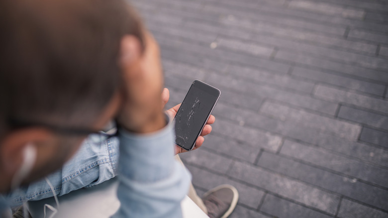 A man with slumped posture is holding a phone