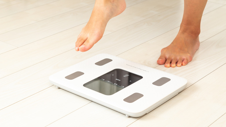 Person preparing to step onto white bathroom scales