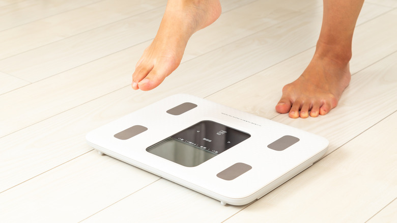 Person preparing to step onto white bathroom scales