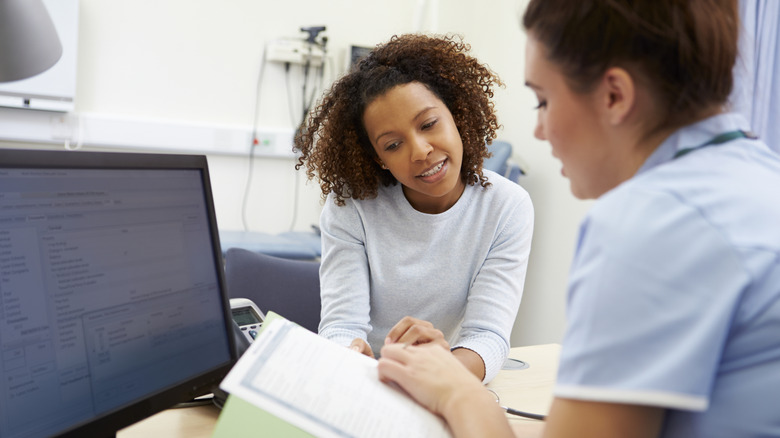 A healthcare professional and patient discussing information on papers