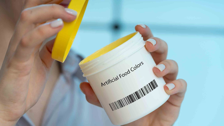 Person opening a pot of articificial food coloring