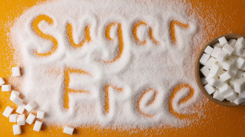 The words "sugar free" written in powdered sugar, with a bowl of sugar cubes at the side