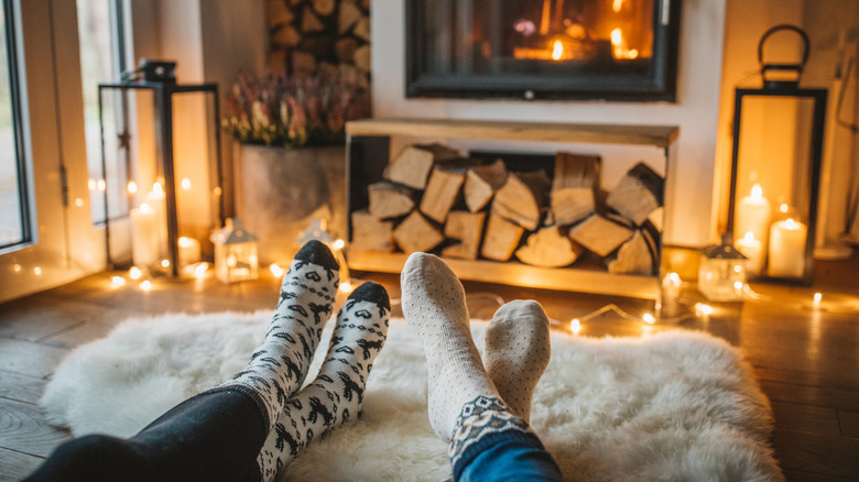 People wearing warm socks lounge in front of a fireplace