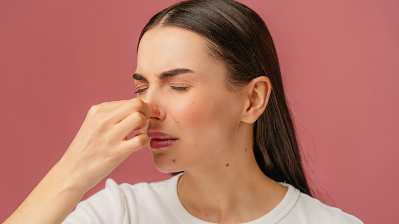 A woman is holding her nose