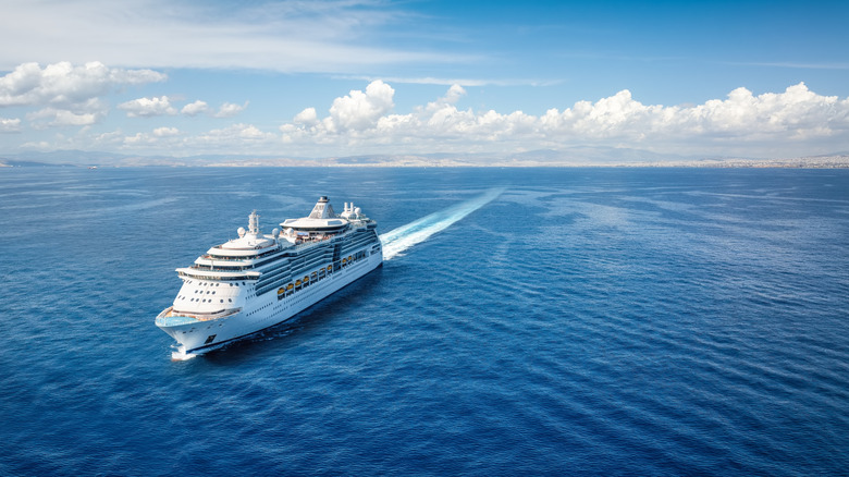 An aerial view of a cruise ship moving through the open ocean.