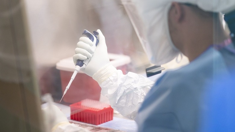 A scientist at Fort Detrick chemical research center in hazmat suit with pipette in hand