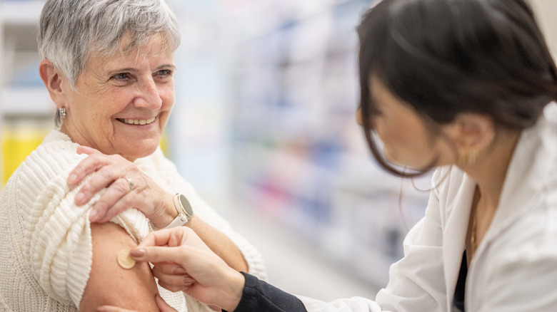 A healthcare provider places a bandage on the arm of a patient.