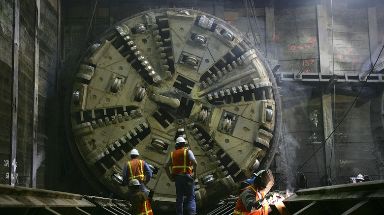 construction workers standing in front of tunnel boring machine