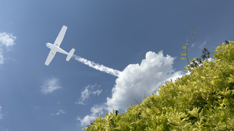 An artistic rendering of a plane leaving chemtrails in a cloud